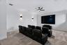 Media room featuring neutral carpeting, a ceiling-mounted fan, dual wall-mounted sconces, and recessed ceiling lighting
