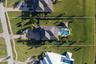 Aerial perspective of a sprawling property featuring a multi-gabled roofline, a paved circular driveway, a rectangular inground pool, and a fully fenc