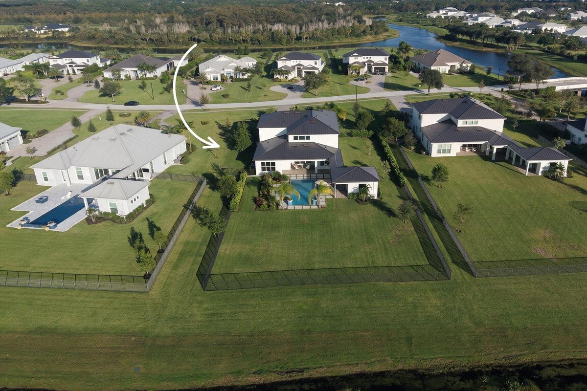 Aerial perspective of property featuring an expansive fenced backyard, private swimming pool, covered lanai, and multi-level roofline