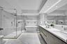 Bathroom featuring a glass-enclosed walk-in shower, freestanding soaking tub, dual-sink vanity with stone countertop, recessed wall shelving, and larg