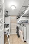Storage area featuring tile flooring, louvered door, integrated metal shelving, and a wall-mounted wooden shoe rack