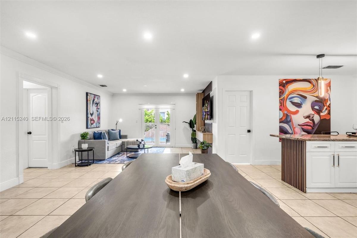 Open floor plan featuring recessed lighting, tile flooring, glass-paned double doors, and a kitchen island with vertical wood-slat detailing