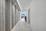Hallway featuring stone-finish flooring, a decorative textured accent wall, and recessed architectural ceiling lighting