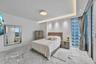 Large-format stone flooring, recessed ceiling lighting with cove accent, floor-to-ceiling glass paneling, and a contemporary flush-mount light fixture