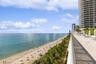 Elevated stone-paved terrace featuring a metal railing, overlooking the coastline and ocean