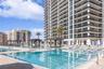 Multi-level outdoor pool deck featuring integrated shade structures, stone-paver decking, and metal handrails