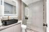 Bathroom featuring a matte black vessel sink, gold-toned faucet hardware, wall-mounted LED-backlit mirror, vertical slat accent wall, and a walk-in sh
