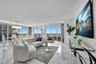 Open-concept living space featuring floor-to-ceiling windows, polished stone flooring, recessed lighting, and a multi-tiered crystal chandelier