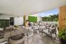 Covered outdoor terrace featuring stone tile flooring, structural columns with wood-finish cladding, and integrated artificial greenery wall accents