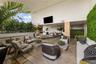 Covered outdoor terrace featuring natural stone tile flooring, structural wooden columns, a mounted television, and integrated vertical greenery