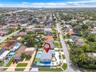 Aerial perspective of a property featuring an in-ground swimming pool, a private sports court, a paved driveway, and mature perimeter landscaping
