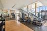 Fitness center featuring floor-to-ceiling windows, open-tread staircase with glass railings, recessed ceiling lighting, and mixed flooring surfaces