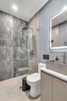 Walk-in shower with floor-to-ceiling stone-patterned tile, frameless glass panel, and rainfall showerhead