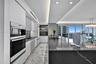 Kitchen featuring high-gloss cabinetry, stone-finish countertops, integrated double wall ovens, recessed ceiling lighting, and floor-to-ceiling window