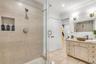 Walk-in shower featuring floor-to-ceiling tile, a built-in recessed storage niche, and a glass enclosure, paired with a custom vanity cabinet and fram