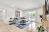 Living area featuring large-format ceramic tile flooring, crown molding, recessed lighting, a custom built-in wood-finish media console, and double gl