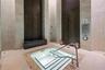 Indoor spa featuring a tiled plunge pool with metal handrail, stone tile walls, built-in bench seating, and an integrated shower head