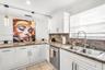 Kitchen featuring white shaker-style cabinetry, patterned stone countertops, stainless steel dual-basin undermount sink, gooseneck pull-down faucet, a