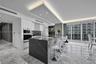 Kitchen featuring a waterfall-edge stone island, built-in dual ovens, recessed tray ceiling lighting, stone flooring, and floor-to-ceiling windows