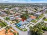 Corner-lot property featuring a concrete driveway, multi-color hardcourt surface, swimming pool, and low-slope roof