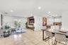 Open-concept interior featuring light-toned tile flooring, recessed ceiling lighting, a custom built-in media console with wood-slat detailing, white 