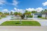 Single-story exterior featuring a stamped concrete driveway, lush palm tree landscaping, and perimeter privacy fencing