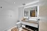Floating vanity featuring a wood-finish countertop, white rectangular vessel sink, integrated LED mirror lighting, and vertical-slat wall paneling
