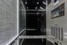 Modern elevator cab featuring stainless steel paneling, textured wall treatments, integrated recessed lighting, and a brushed metal handrail