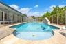 In-ground swimming pool with stone-tiled decking, integrated water feature, and a shallow sun shelf