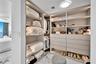Custom walk-in closet featuring floor-to-ceiling built-in cabinetry, integrated LED shelf lighting, multiple soft-close drawers, and marble-finish flo