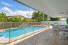 Covered patio with paver flooring, swimming pool with integrated water feature, and perimeter privacy fencing