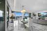 Open-concept living space featuring stone flooring, floor-to-ceiling glass panel doors, recessed ceiling lighting, and a custom built-in stone console