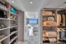 Walk-in closet with extensive custom shelving and integrated hanging rods, featuring stone-finish flooring throughout
