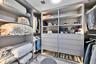 Walk-in closet featuring custom built-in cabinetry with integrated LED lighting, tiered shelving, multiple storage drawers, and floor-to-ceiling organ