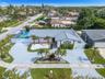 Single-story residence featuring a tile roof, an expansive paved driveway, a gated sports court, and manicured landscaping with mature palm trees