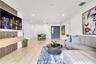 Living area featuring tile flooring, recessed lighting, and a decorative wood-slat accent wall with a wall-mounted floating storage cabinet