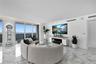 Open-concept living space featuring floor-to-ceiling glass windows, polished stone flooring, recessed ceiling accent lighting, and a built-in electric