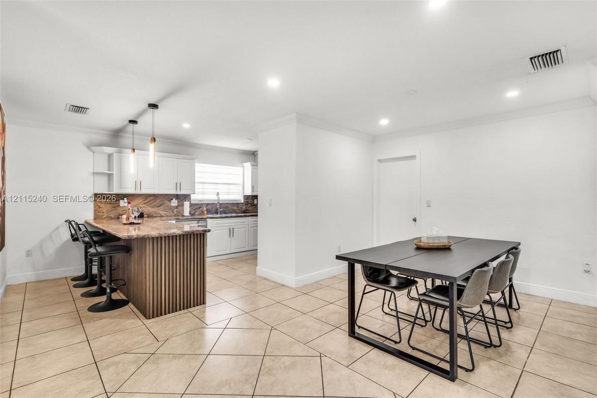 Kitchen featuring white shaker-style cabinetry, stone-surface countertops, decorative wood-slat kitchen island paneling, recessed lighting, and tile f