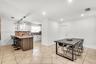 Kitchen featuring white shaker-style cabinetry, stone-surface countertops, decorative wood-slat kitchen island paneling, recessed lighting, and tile f
