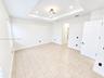 Tray ceiling featuring recessed lighting and a central contemporary light fixture, complemented by tile flooring and a five-panel interior door