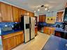 Kitchen featuring warm-tone wood cabinetry, blue solid-surface countertops, a mosaic tile backsplash, stainless steel appliances, and track lighting
