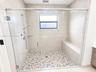 Walk-in shower MASTERS featuring a glass enclosure, pebble-stone flooring, built-in bench, wall-mounted shower head with hand-held attachment, and neu