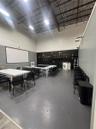 Industrial-style interior featuring high vaulted ceilings with exposed beams, resilient flooring, recessed ceiling lighting, and a wall-mounted projec