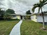 Single-story residence featuring a painted stucco exterior, decorative breeze block wall detailing, an attached garage, and a concrete walkway