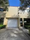 Two-story exterior featuring a stucco facade, single-car garage with a roll-up door, glass-paneled entry door, and large rectangular windows