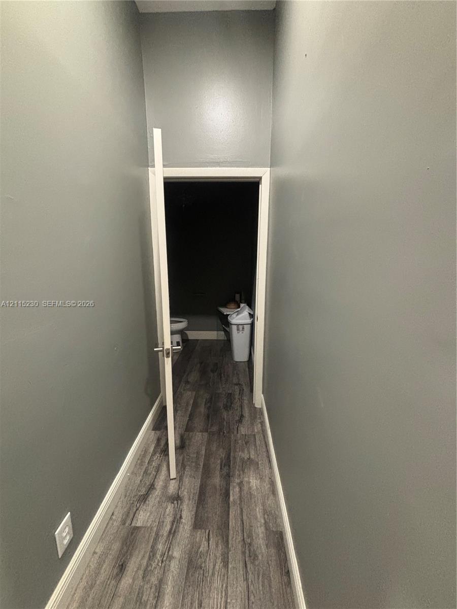 Hallway with wood-finish flooring and grey-toned wall paint