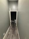 Hallway with wood-finish flooring and grey-toned wall paint