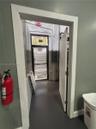 Entryway featuring a solid door, painted gray interior walls, exposed electrical conduit, and a glass-paneled exterior door with integrated horizontal