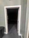 Interior doorway featuring crisp white trim, a solid-core door, and brushed metal hinges