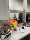 Kitchen featuring stone-surface countertops, full-height stone backsplash, stainless steel range hood, and dark cabinetry